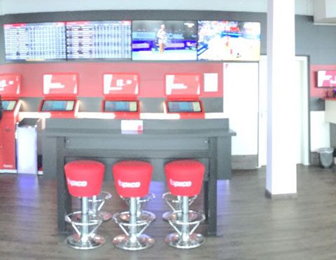 Wettbüro-Theke mit roten Barhockern und Bildschirmen